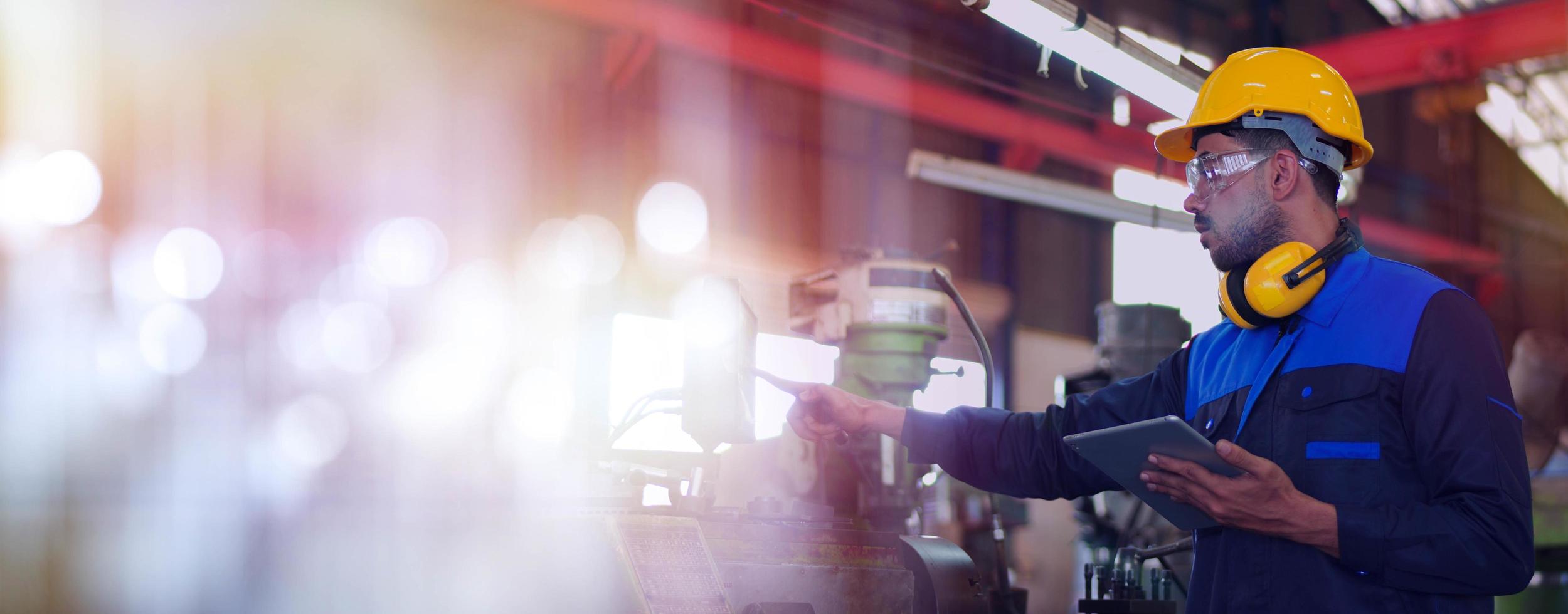 ingeniero de mantenimiento profesional, trabajador técnico, reparador con uniforme, casco de seguridad usando una máquina de control de verificación de computadora de tableta en fábrica. concepto de industria de maquinaria pesada de fabricación. foto