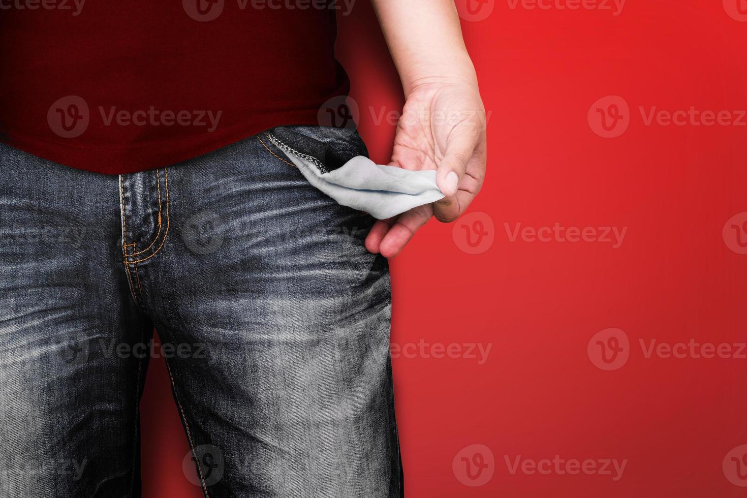 hombre mostrando su bolsillo vacío en el fondo de la pared roja. foto