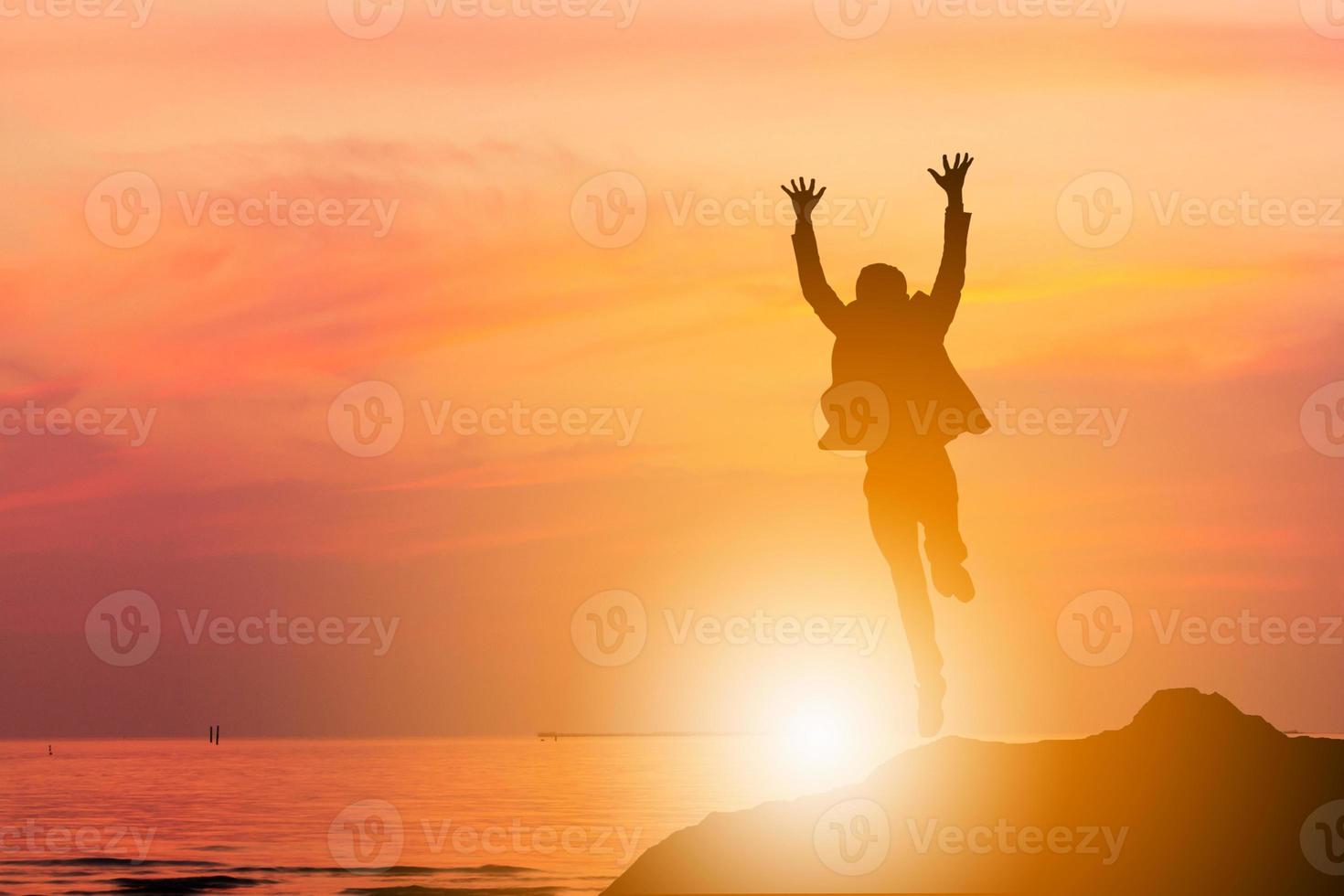 silueta de ingeniero de negocios hombre celebración éxito felicidad en un fondo de atardecer de cielo de piedra, deporte y concepto de vida activa. foto