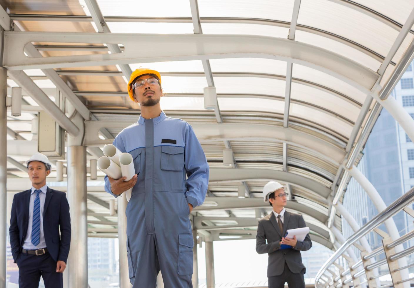 Business team engineer planing with white helmet and holding drawing paper in hand against city background planing and teamwork management concept photo