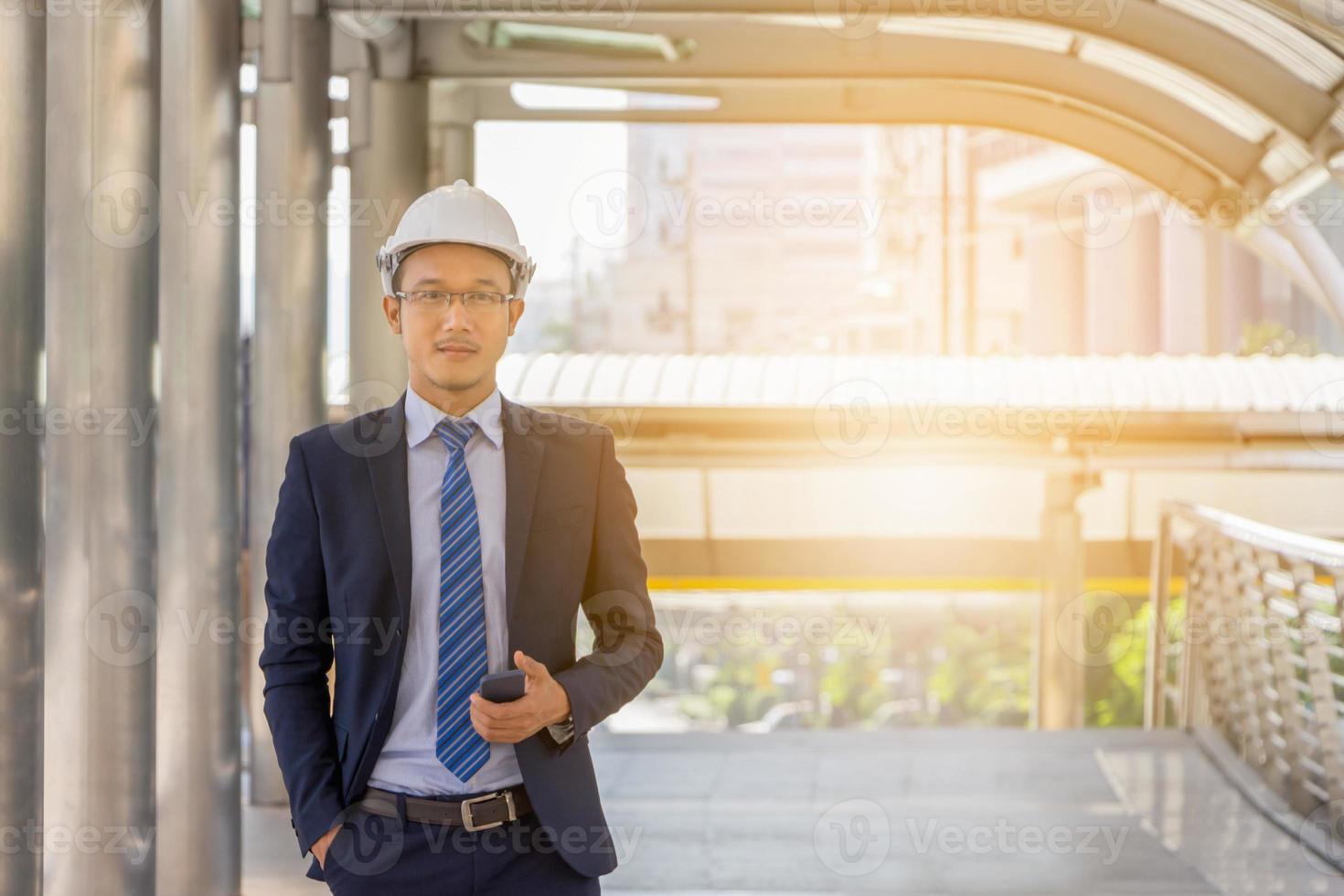 Business engineer planing with white helmet and smartphone in hand against city background planing and management concept. photo