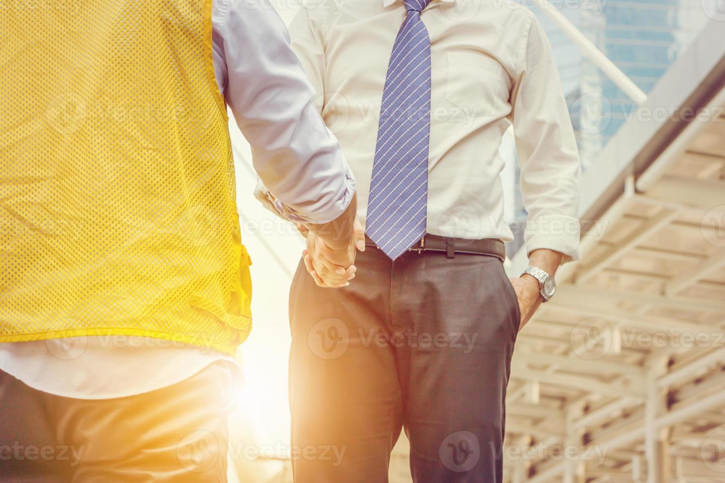 concepto de equipo de éxito y felicidad, empresario y apretón de manos de ingeniería empresarial en el fondo de la ciudad. foto