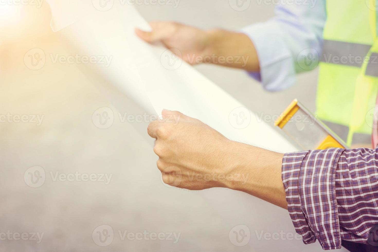 Close up of construction engineers with blueprint in hand working outdoors at construction site with copy space photo