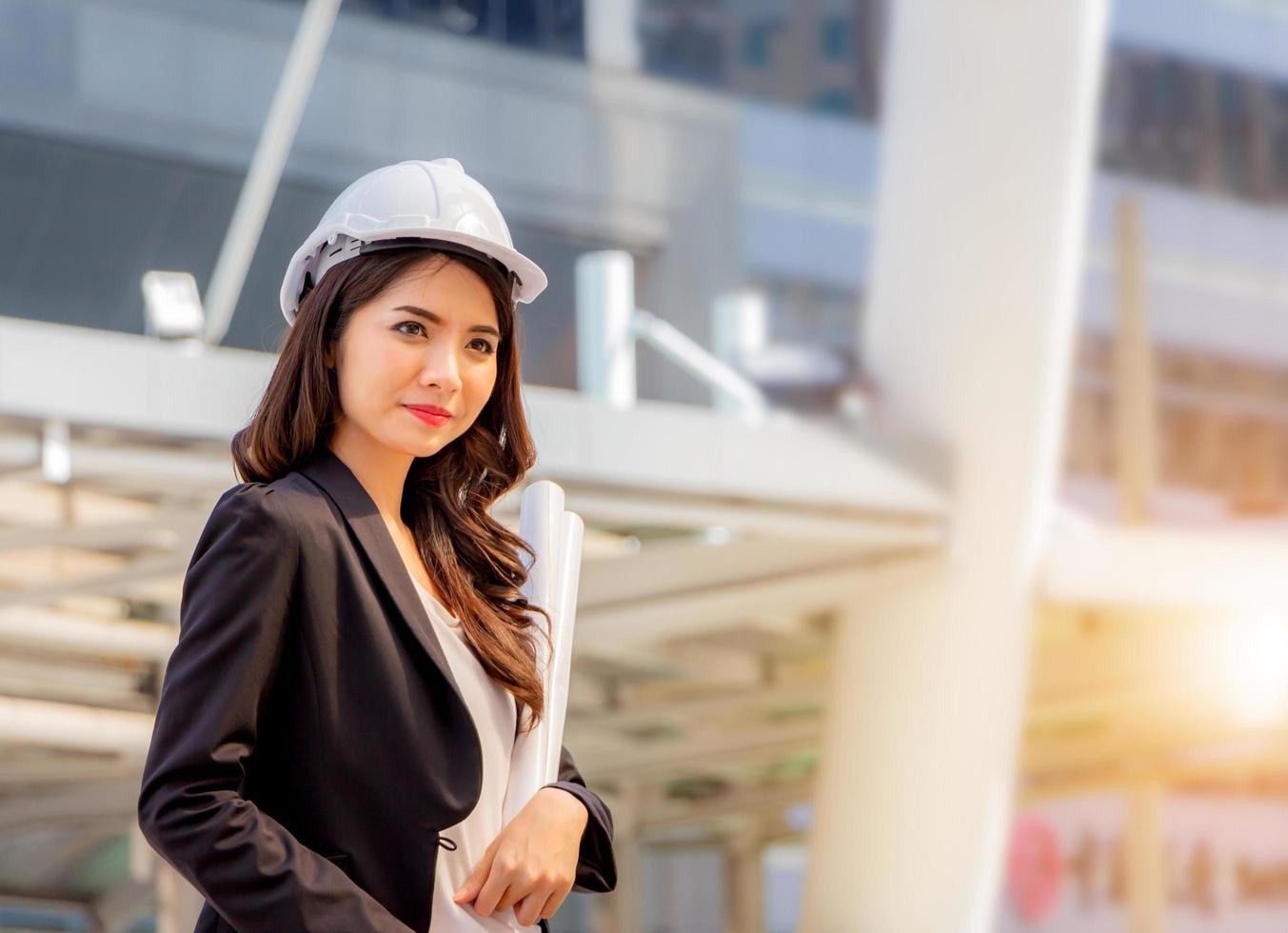 la construcción y el mantenimiento piensan en un gran concepto, una arquitecta con casco blanco y un fondo borroso de la ciudad foto