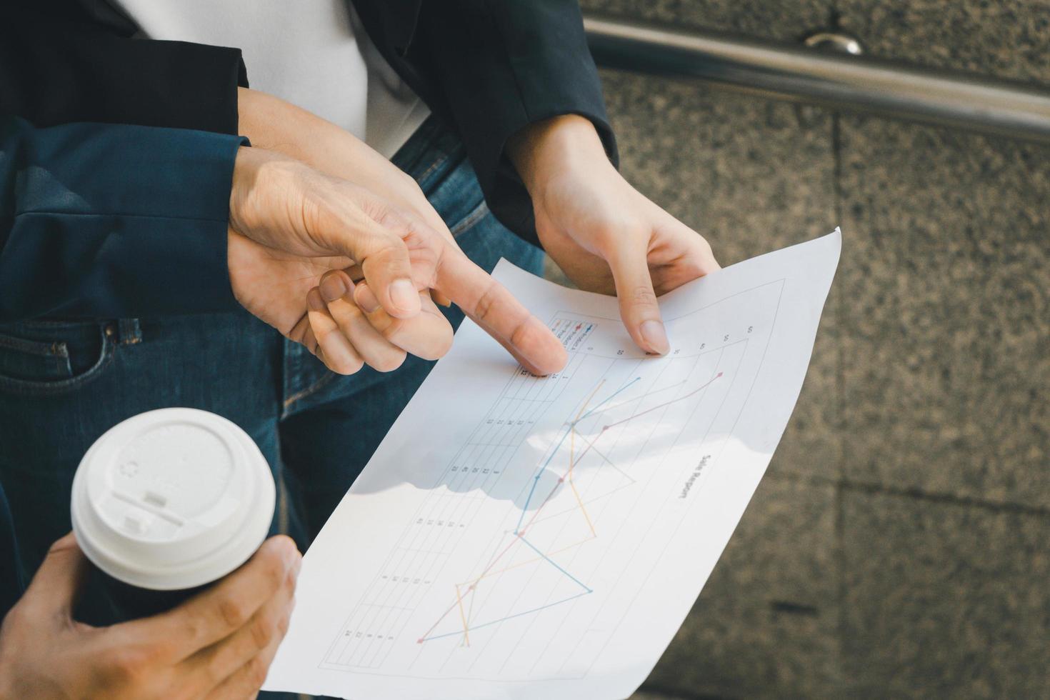 Businessman and business woman walking outside office with paper sheet and coffee cup in hand. photo