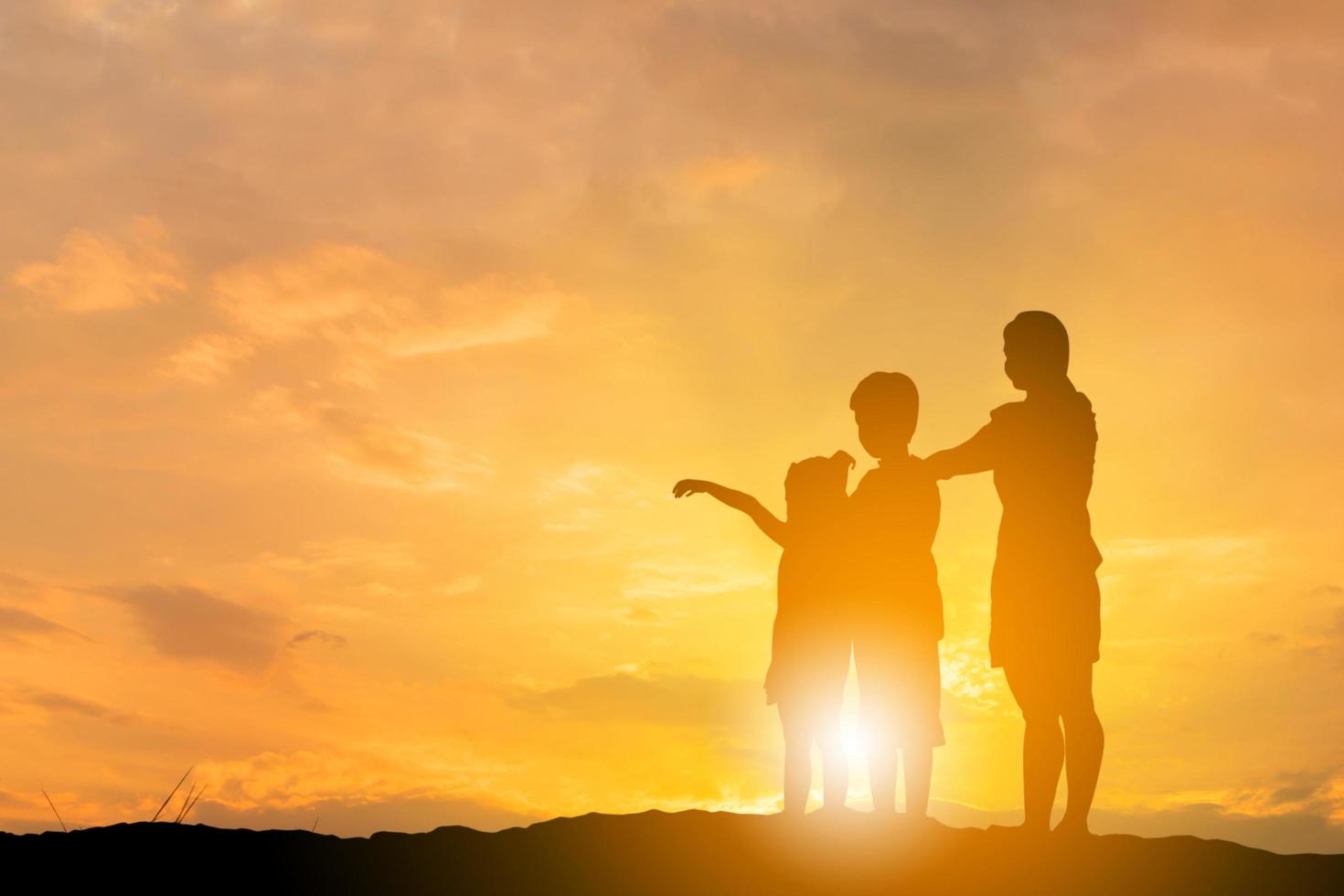 la silueta de hermano y hermana corrió hacia la madre al fondo de la puesta de sol, feliz concepto de madre e hijo, con camino de recorte. foto