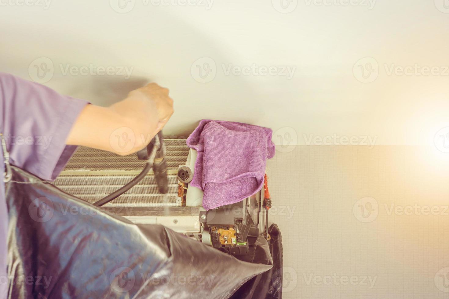Technician repairing and cleaning dust filled air conditioning unit filters with water photo