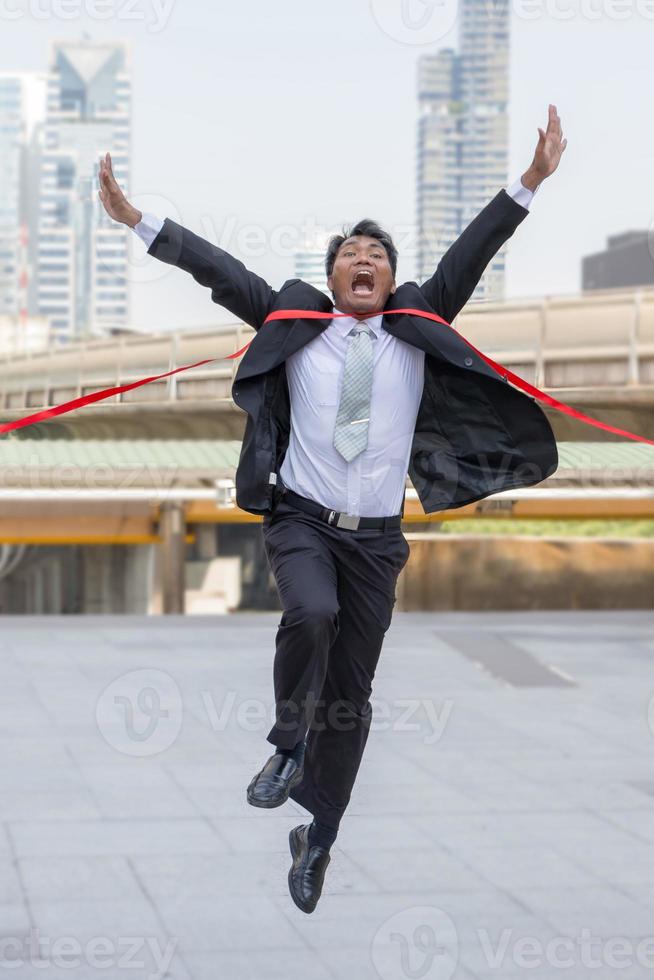 concepto de éxito y felicidad, alegre hombre de negocios cruzando la línea de meta del fondo de la ciudad de la pista de carreras. foto