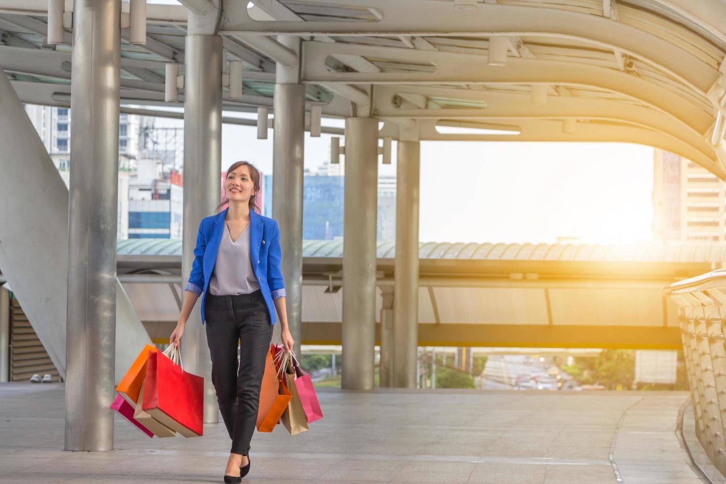 young woman carrying shopping bags while walking along the street. Happy Life Style Concept. photo