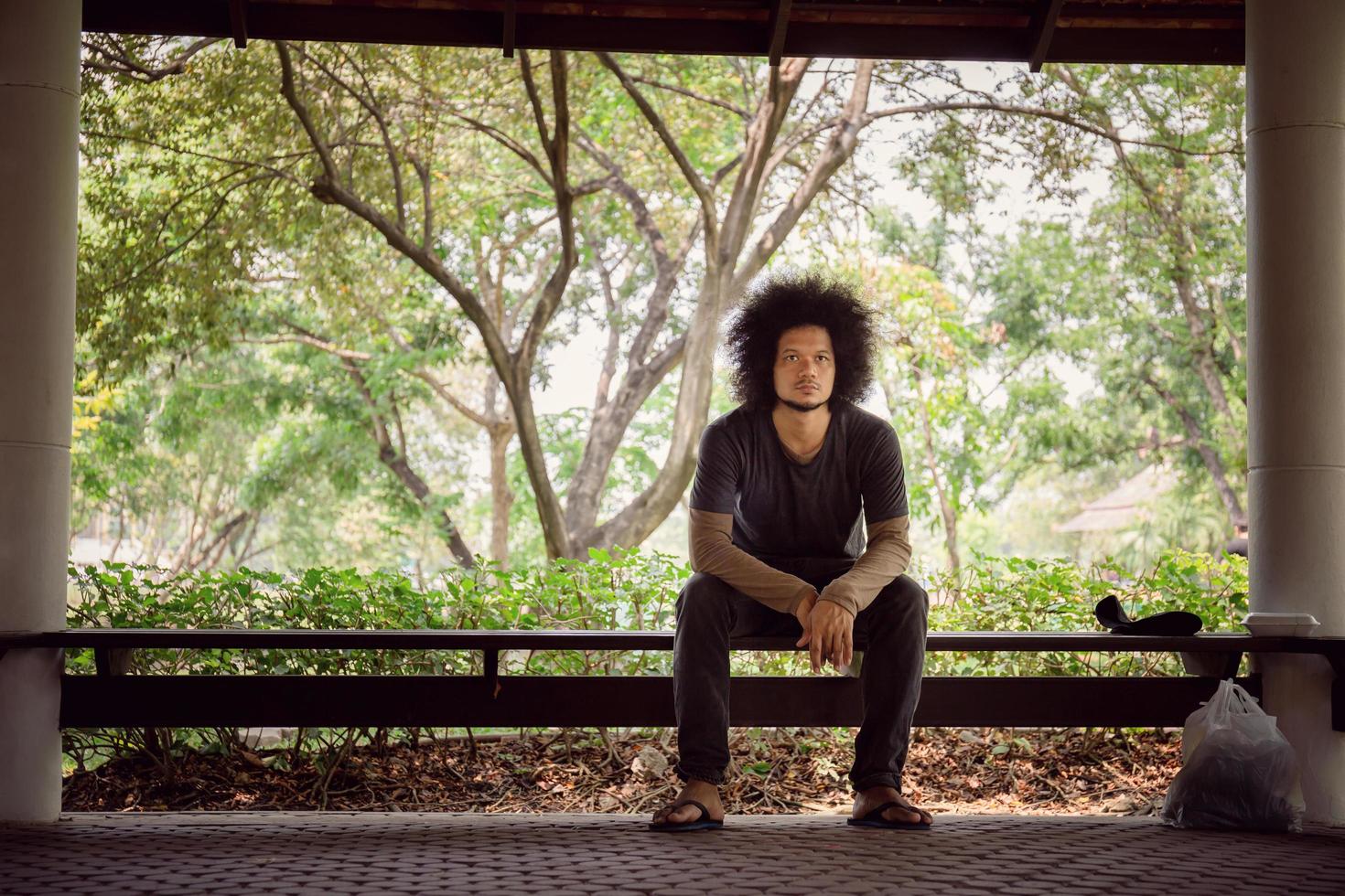 Homeless man sitting on the floor in the cities park. photo