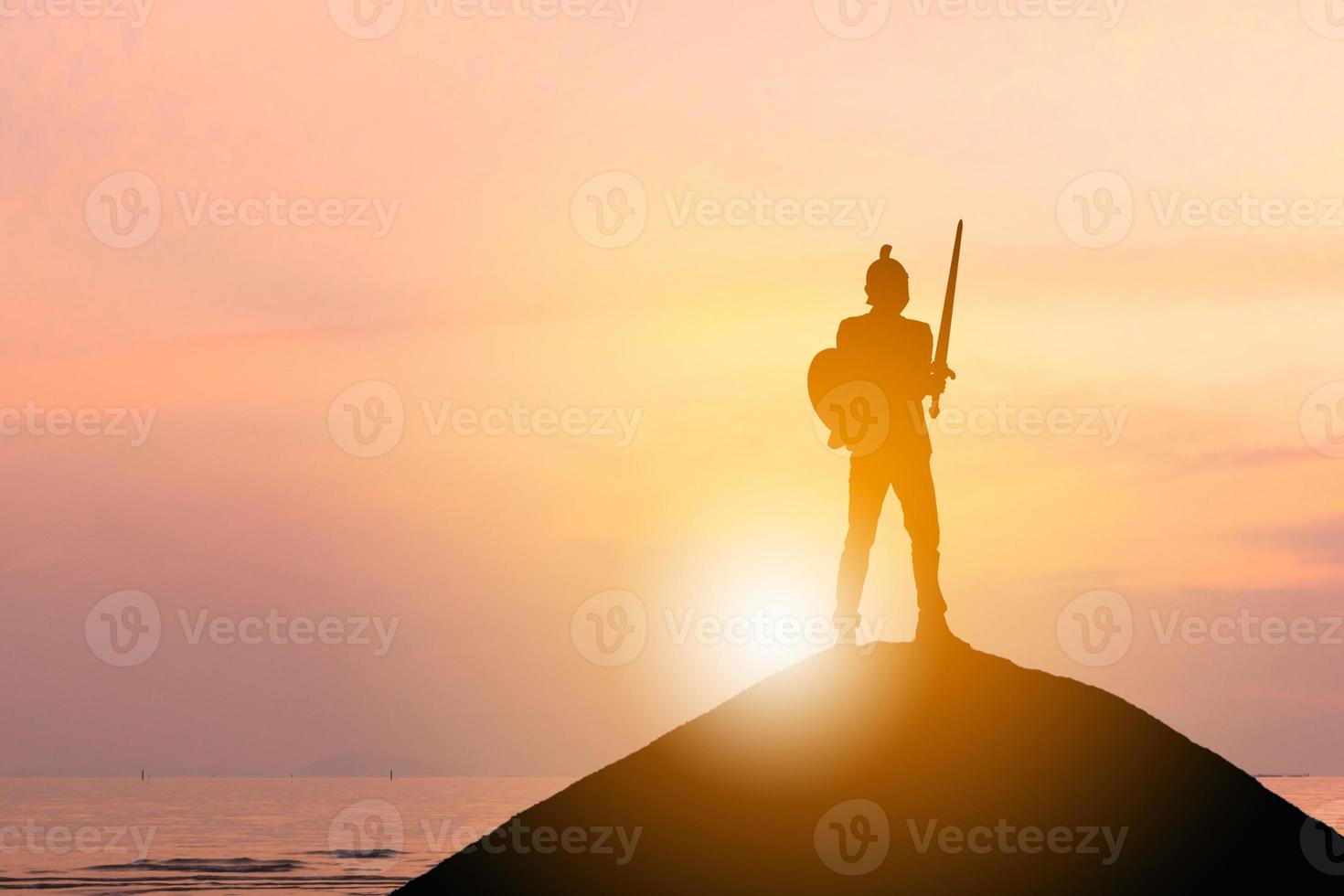 Silhouette of Businessman Knight Sword and Shield in Sunset Background, Fighting Business Warrior Concept. photo