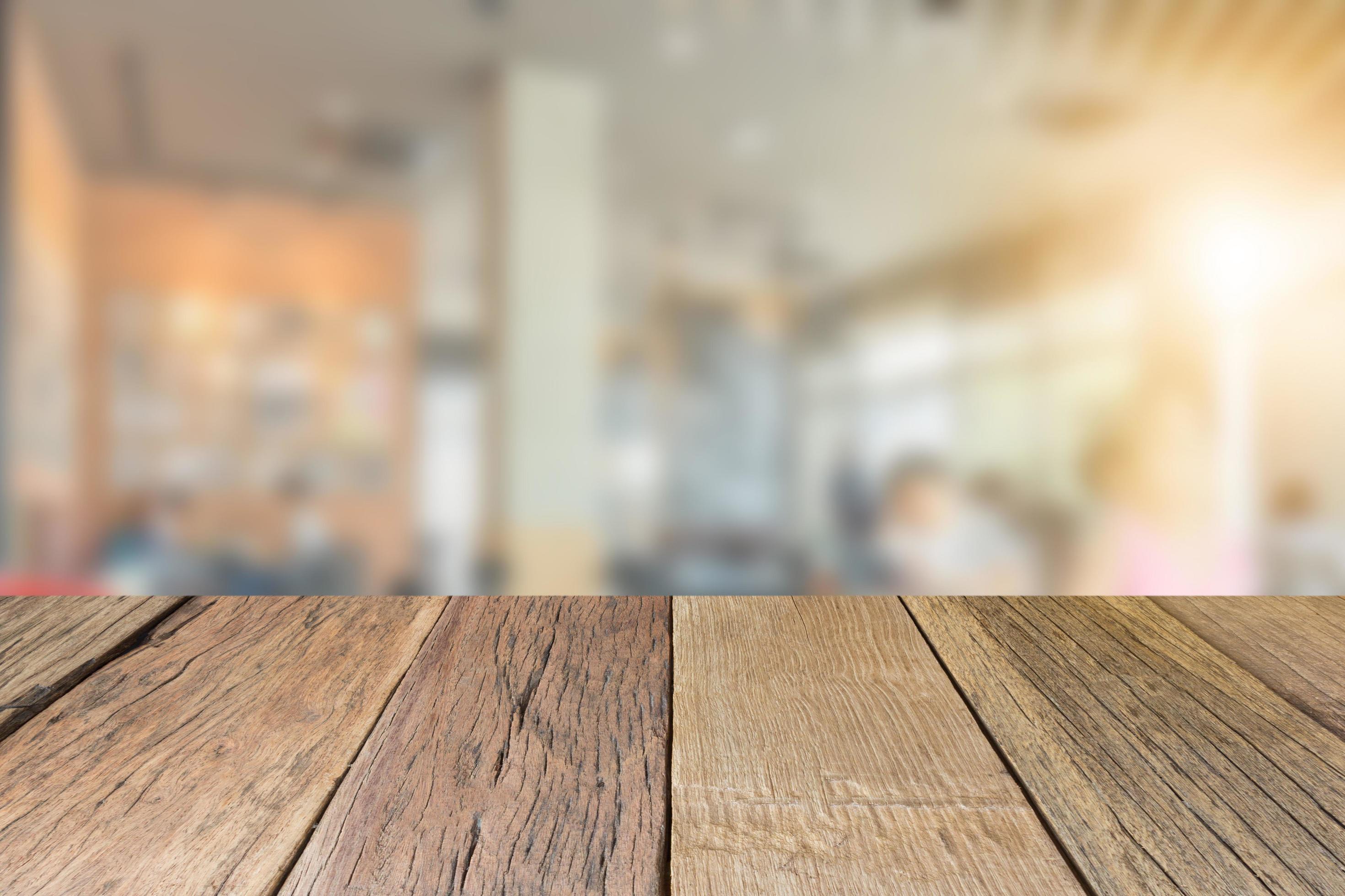 Empty wooden table top perspective with blur coffee shop background, used for montage or display