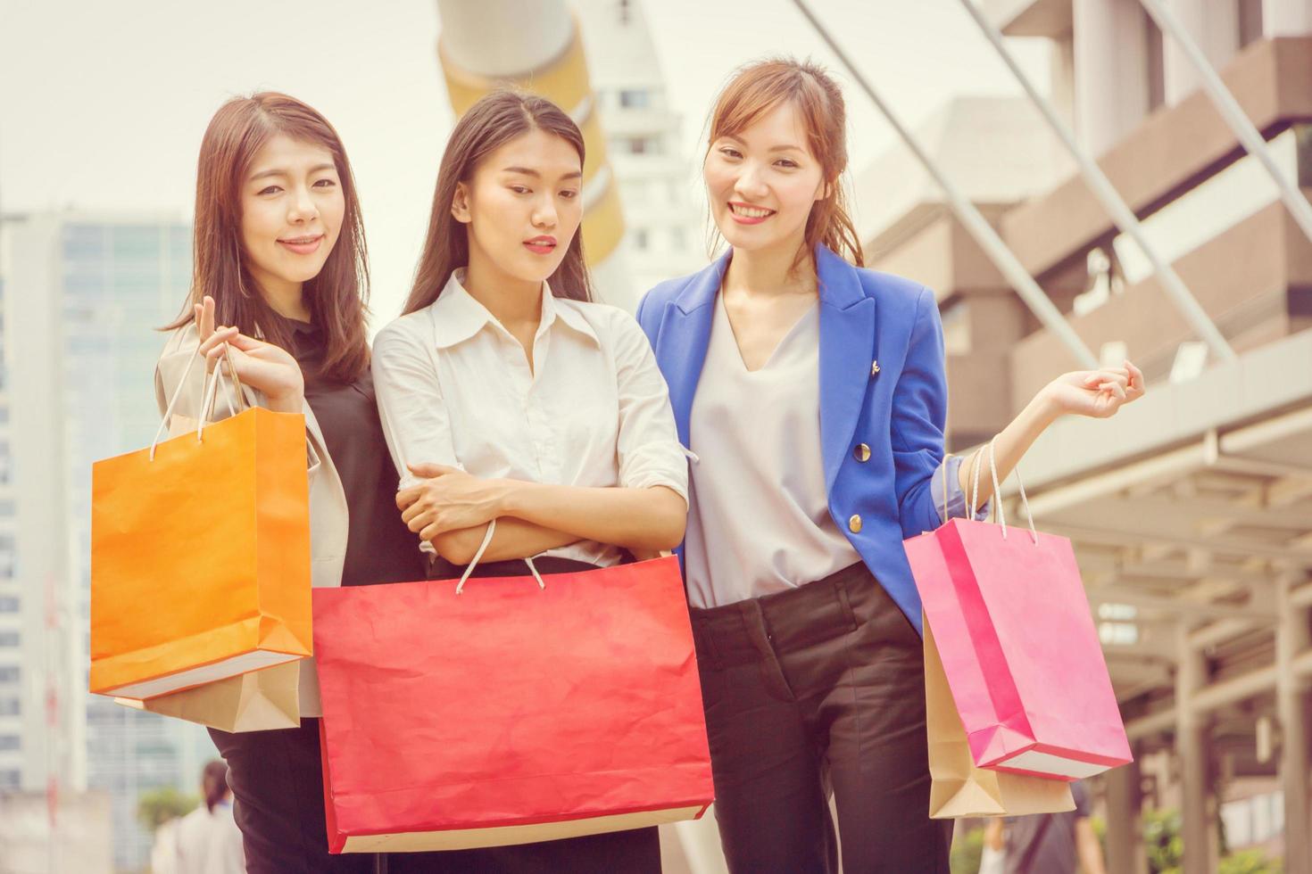 Happy Shopping three beautiful young female Friends with bags on the street. Group of caucasian women purchasing in the city. photo