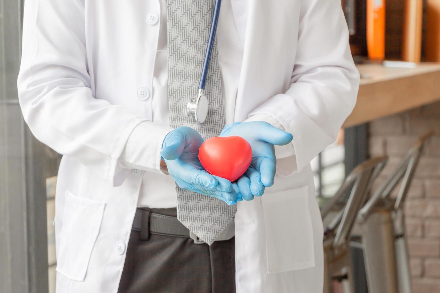 Close up of Male doctor with stethoscope and protect red heart in his hands, healthcare concept. photo