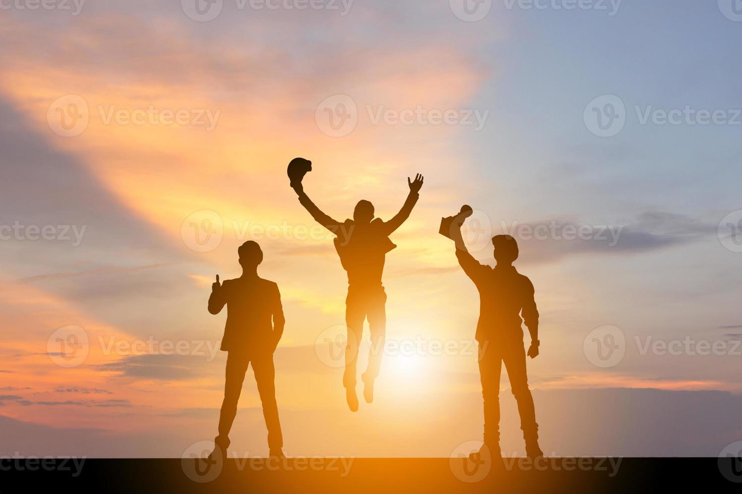 silueta de ingeniero de negocios hombre equipo celebración éxito felicidad en el fondo de la puesta de sol del cielo nocturno, trabajo en equipo de éxito y concepto de vida activa. foto