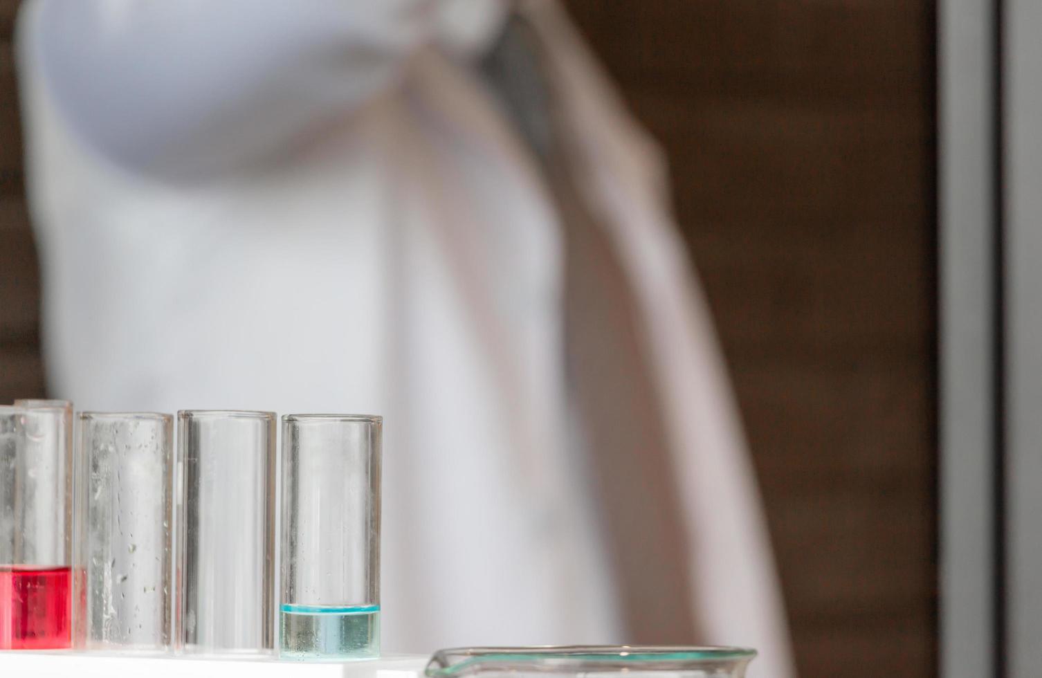 Medical test tubes with fluid blurred scientist in a laboratory background photo