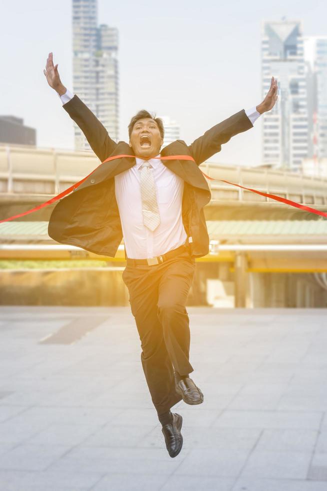 Success and Happiness concept, Cheerful business man crossing the finish line of racing track city background. photo