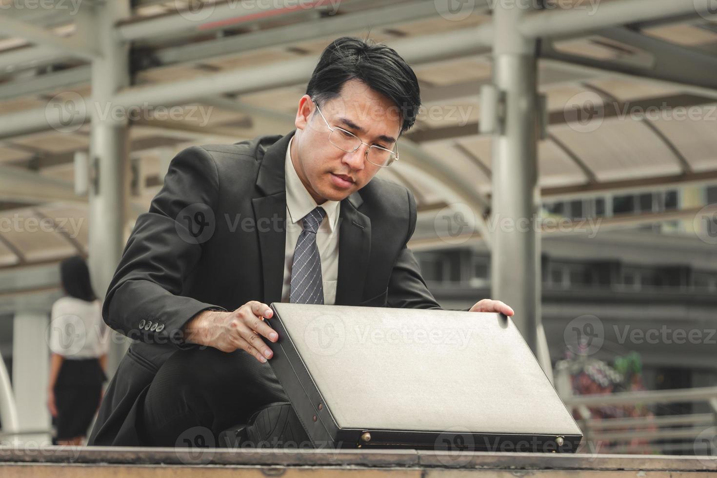 Close up of depressed businessman sitting on floor looking a suitcase, Failure and despair concept photo