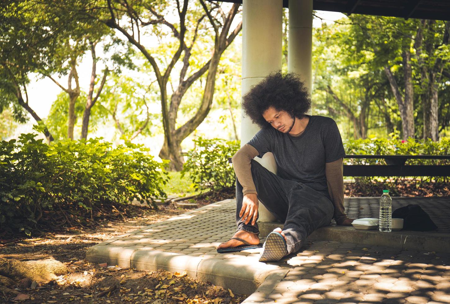 Homeless man sitting on the floor in the cities park. photo