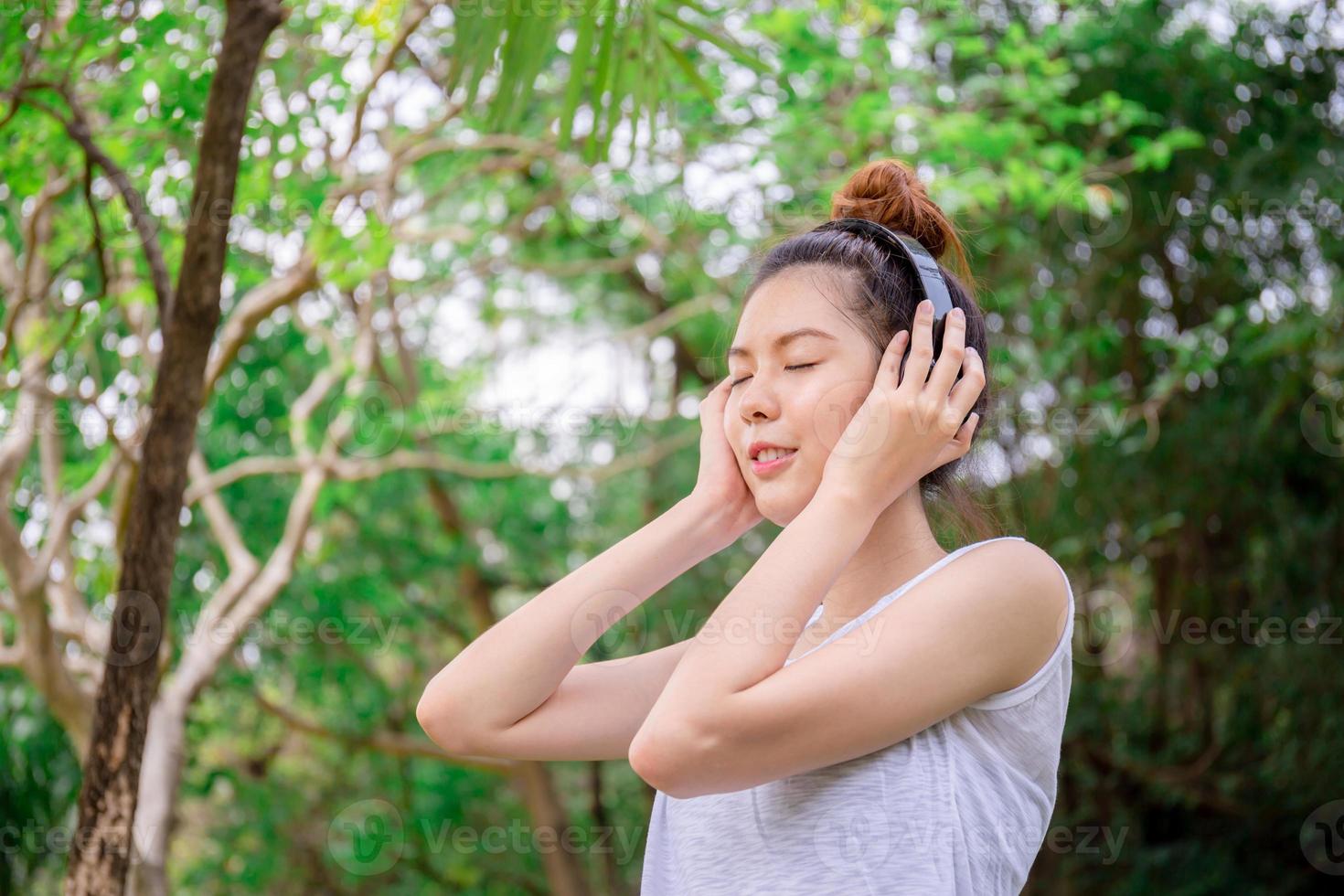 hermosa joven con auriculares disfrutando y relajada en la música en el parque foto