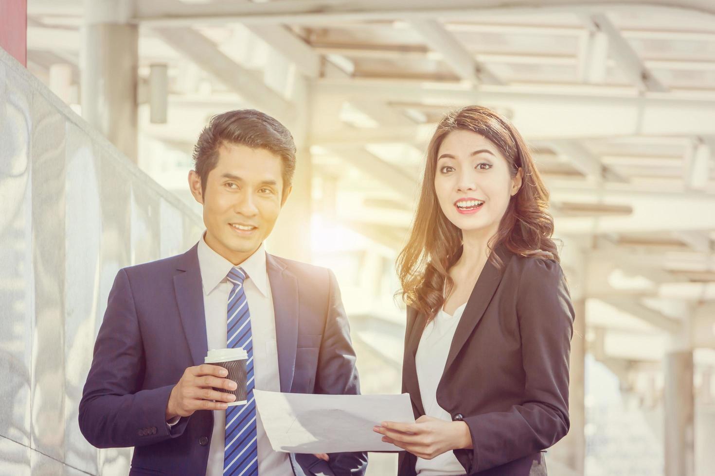 Close up of Happiness businessman with coffee cup and business woman with sheet in hand blurred city background, Success team concept. photo