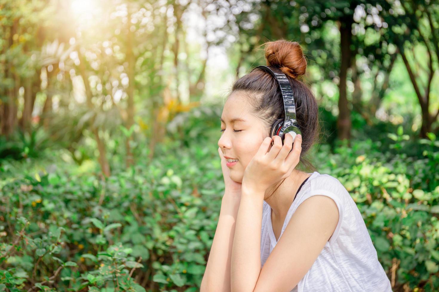 Beautiful young woman with headphones enjoying and relaxed in music in the park photo