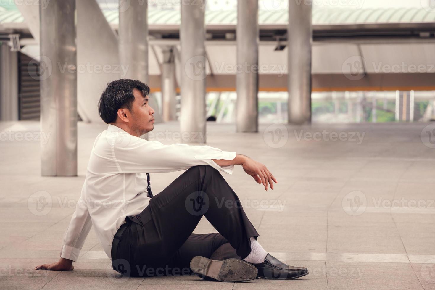 Lonely businessman lost in depression on the floor in the city, feeling Inattentive and sadness concept. photo