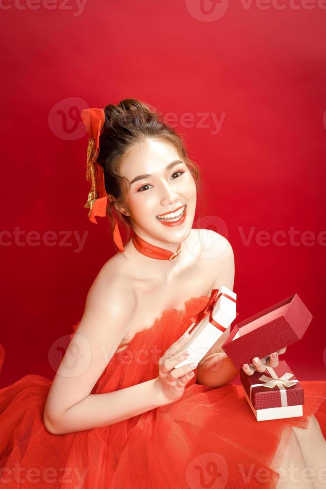 Young Asian pretty woman model in a posh stylish luxury red dress on a red background isolated. photo