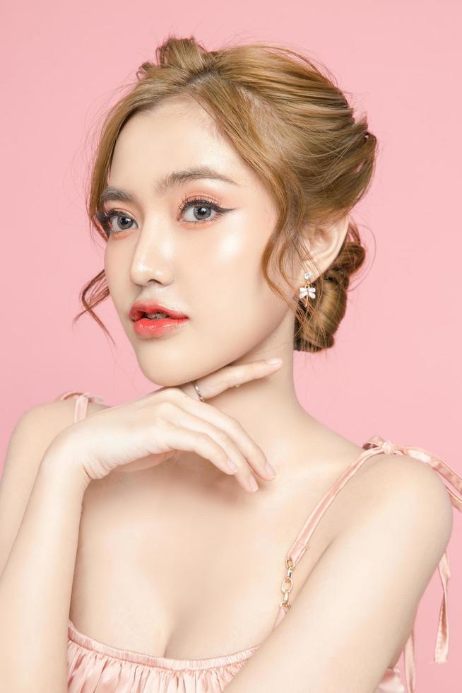 Beautiful young Asian woman have glitter on face wearing braces is feeling happy with clean fresh skin on pink background. Plastic surgery, Anti ageing, Cosmetology, beauty and spa, Female portrait. photo