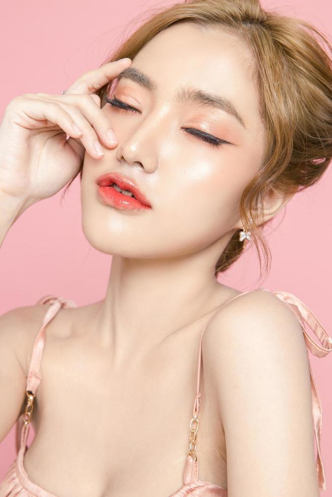 Beautiful young Asian woman have glitter on face wearing braces is feeling happy with clean fresh skin on pink background. Plastic surgery, Anti ageing, Cosmetology, beauty and spa, Female portrait. photo