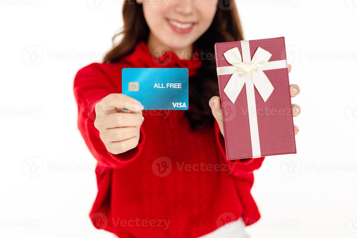 una linda mujer asiática con un vestido rojo con un sombrero de santa sostiene una caja de regalo. concepto de compras. foto