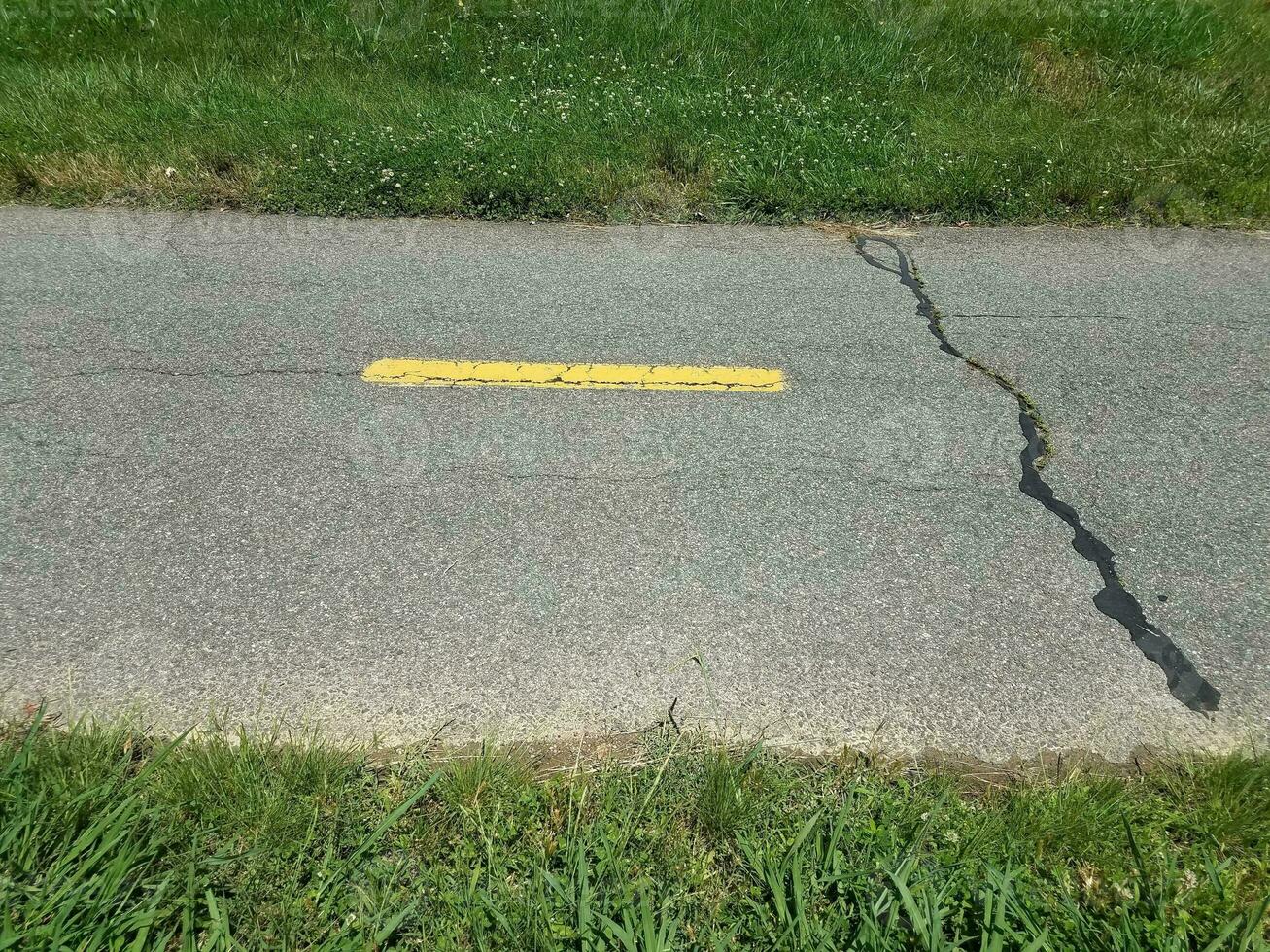 asphalt bike path with yellow line and crack photo