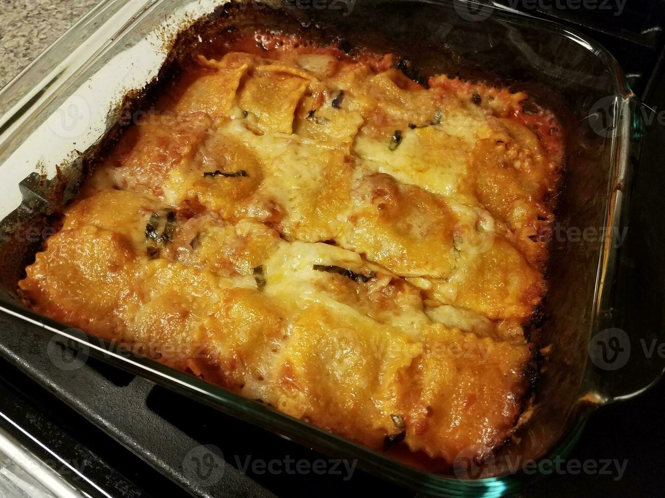 baked ravioli pasta with cheese in glass container on stove photo