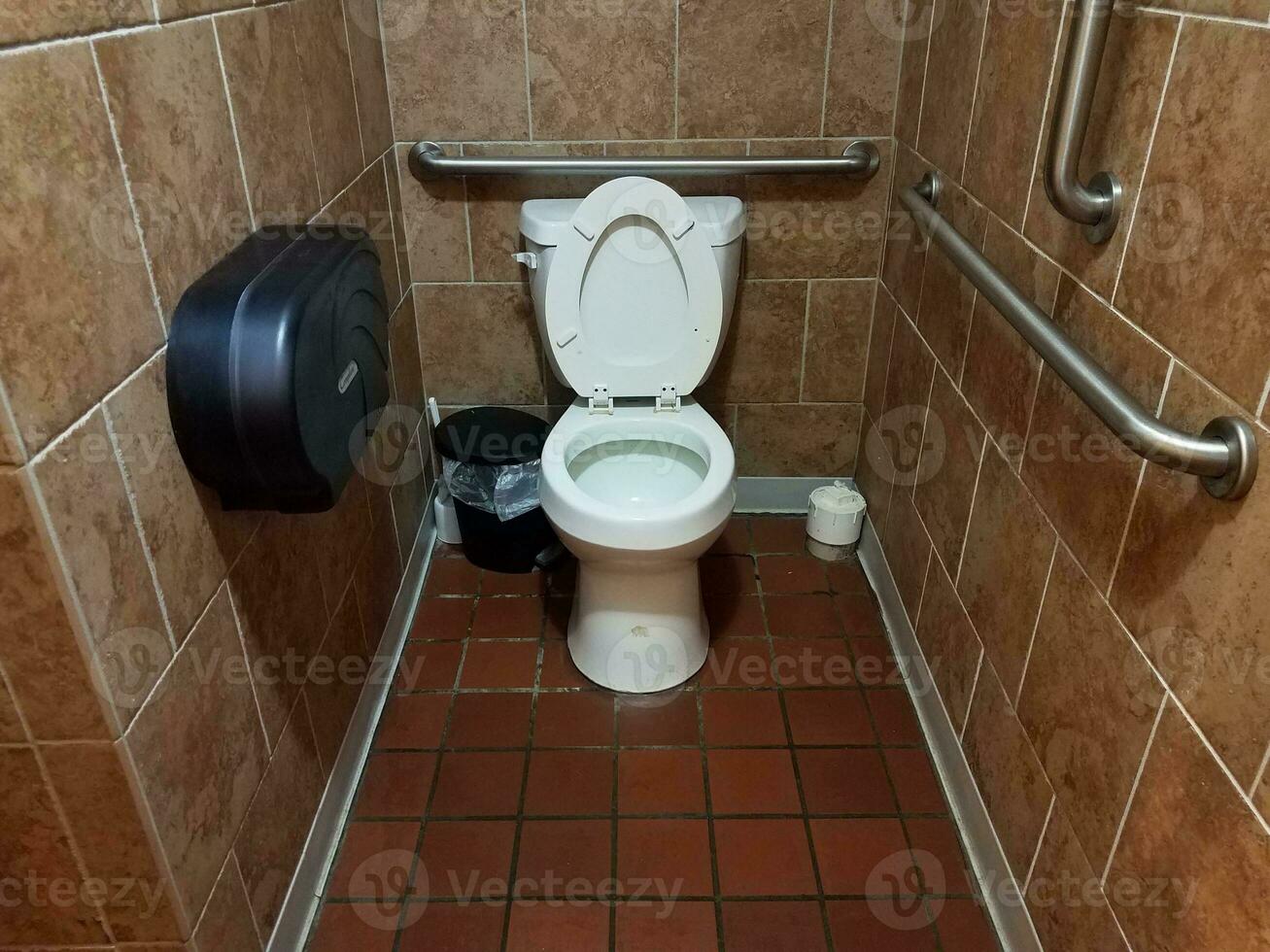 bathroom stall with toilet and tiled floors photo