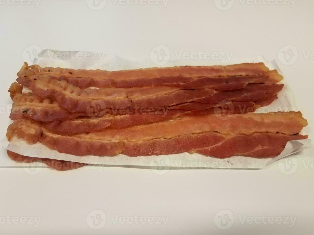 strips of bacon and paper on white surface or table photo
