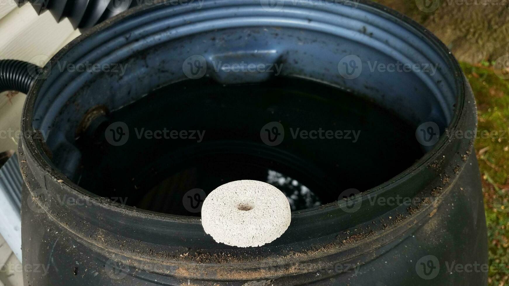 Insecticida de tableta de mosquito blanco circular en el borde del barril de lluvia foto