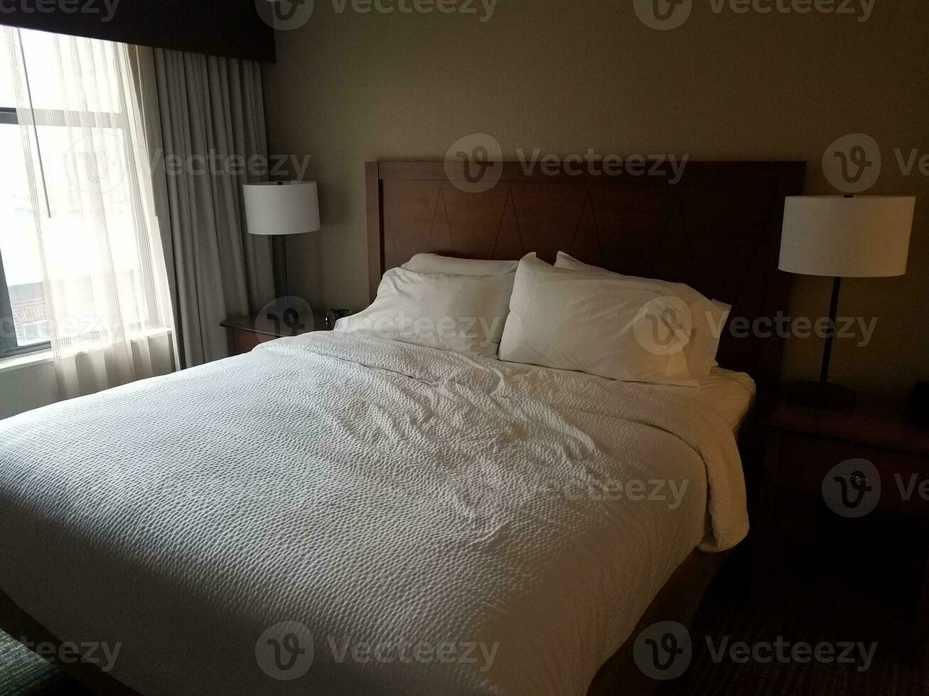 bed in room with white covers and lights and window photo