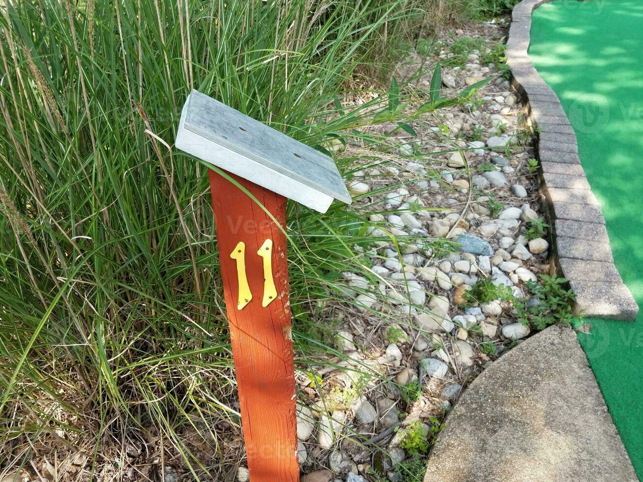 number 11 sign with surface on wood post on miniature golf course photo