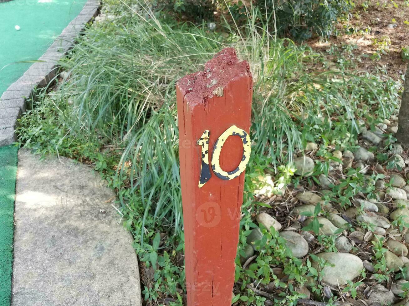 number 10 sign with surface on wood post on miniature golf course photo