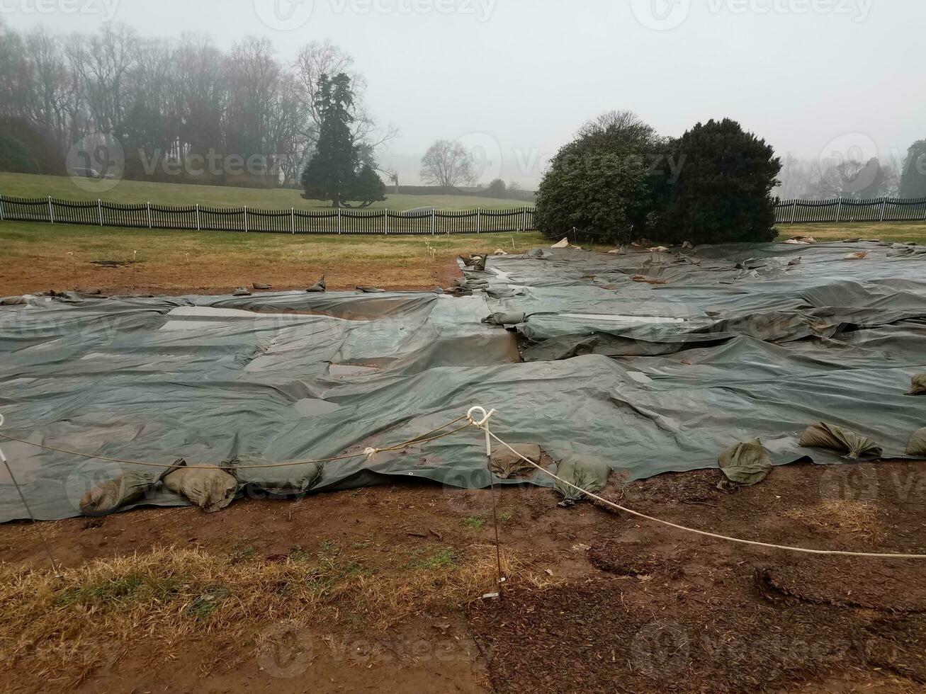 plastic tarp on wet ground with sandbags at dig site photo