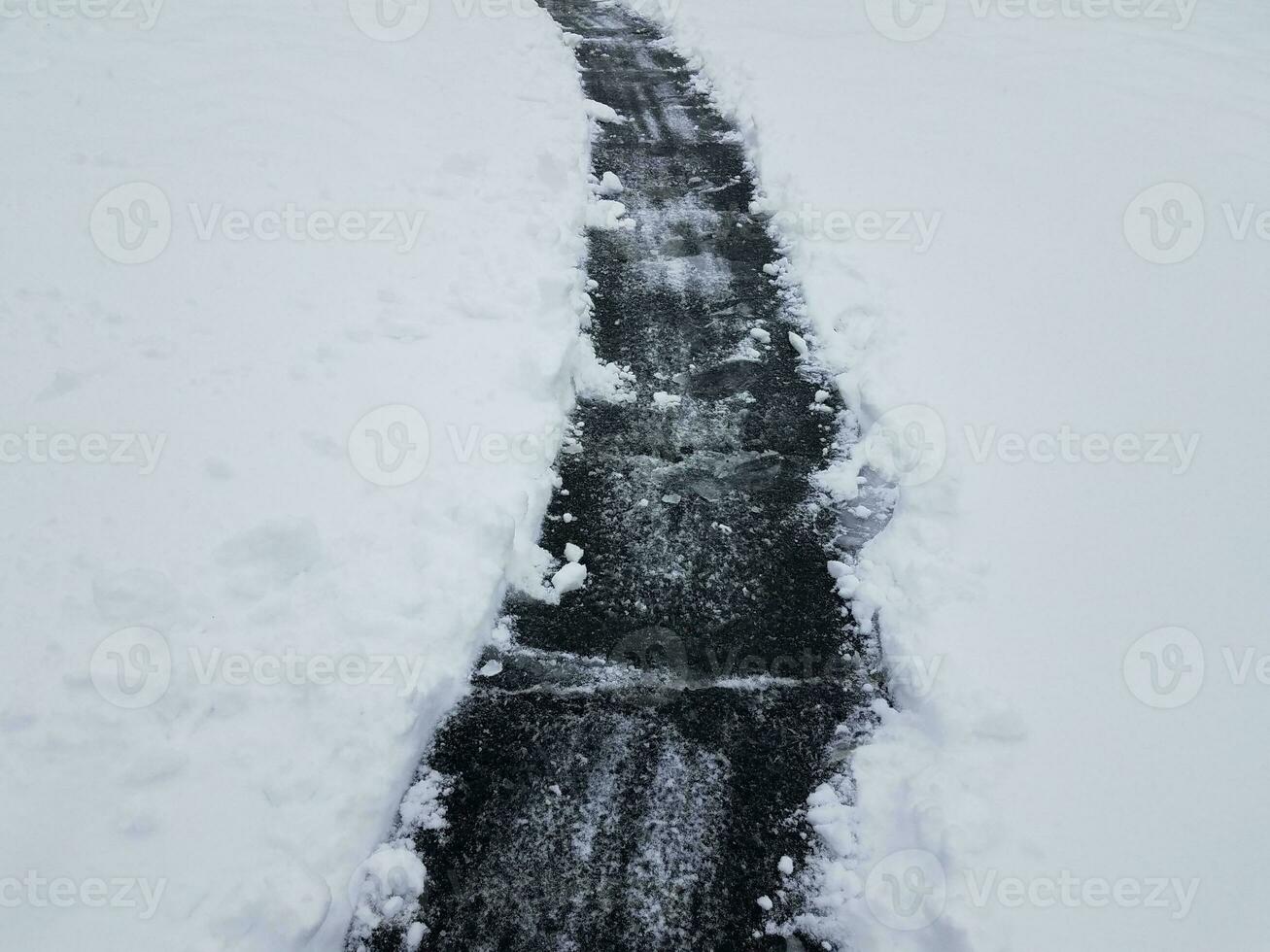 asphalt driveway with white snow shoveling in winter photo