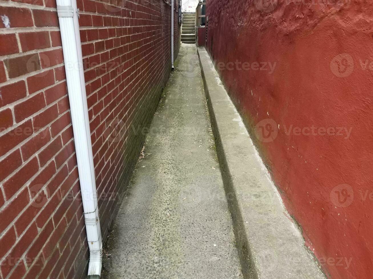 callejón estrecho con pared roja y ladrillos sobre mampostería foto