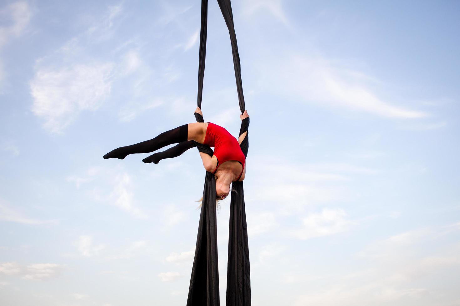 exercises with aerial silk outdoor, sky background. beautiful fit woman training acrobatic in airt. photo