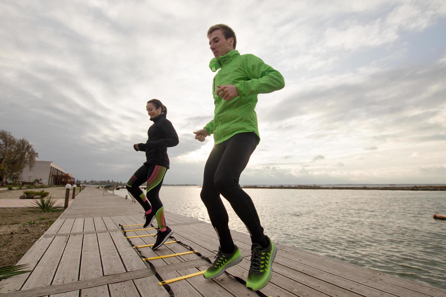 group of young people training outdoors, runners exercises, sea or river background photo