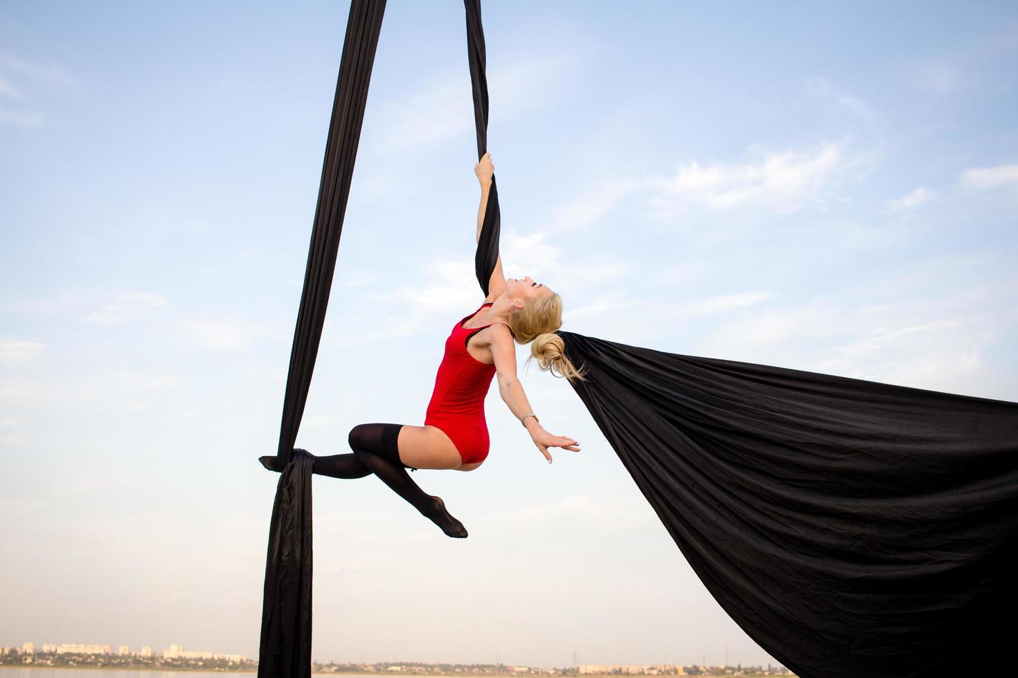 exercises with aerial silk outdoor, sky background. beautiful fit woman training acrobatic in airt. photo