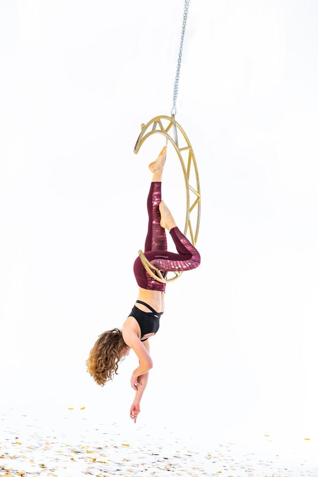 Woman hanging in aerial silk in white studio photo