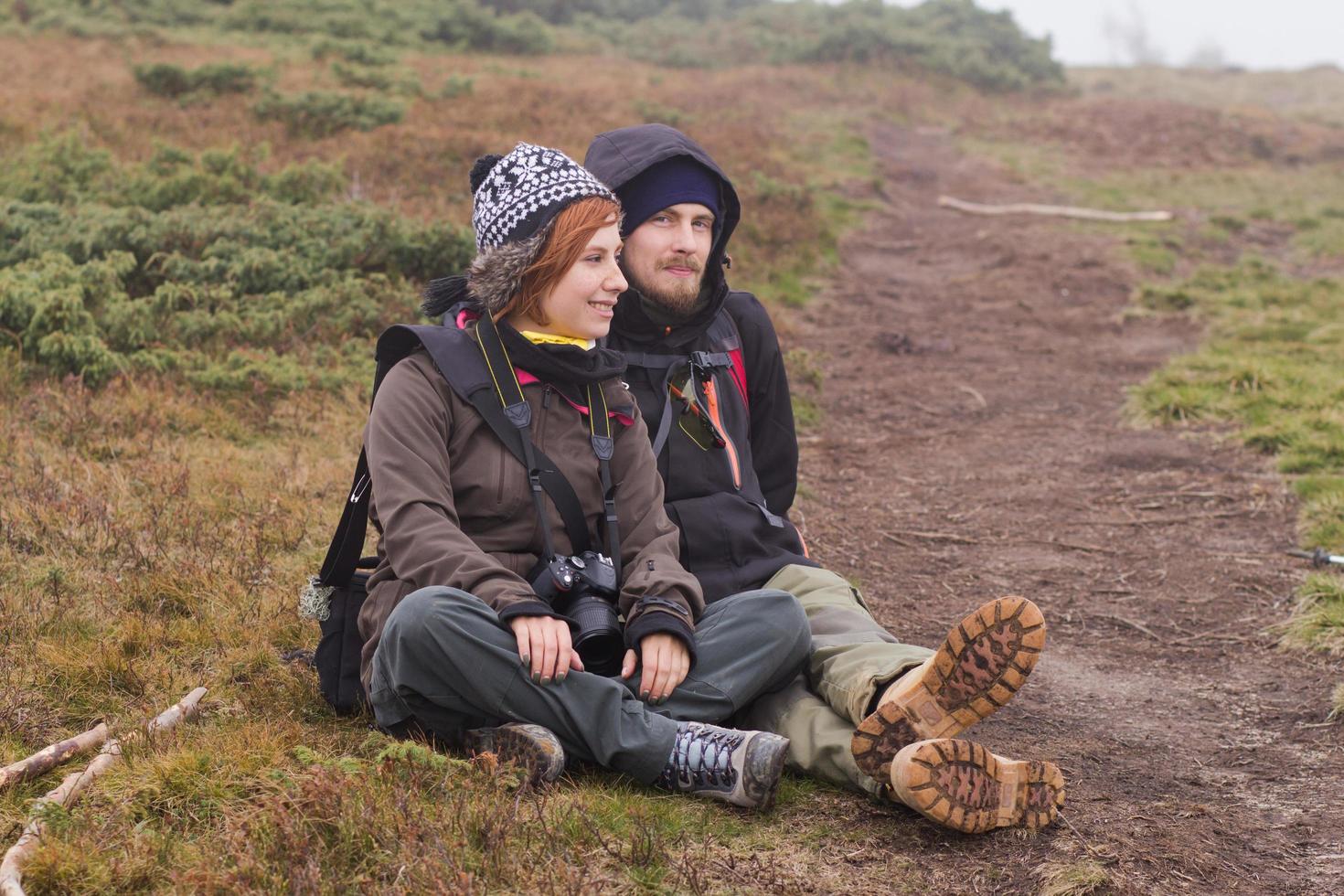 Young couple hikers with thermos cups in forest, travelers in mauntains drinking tea or coffee photo
