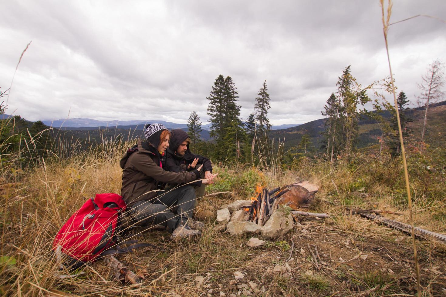 pareja joven excursionistas con tazas termos en el bosque, viajeros en mauntains bebiendo té o café foto