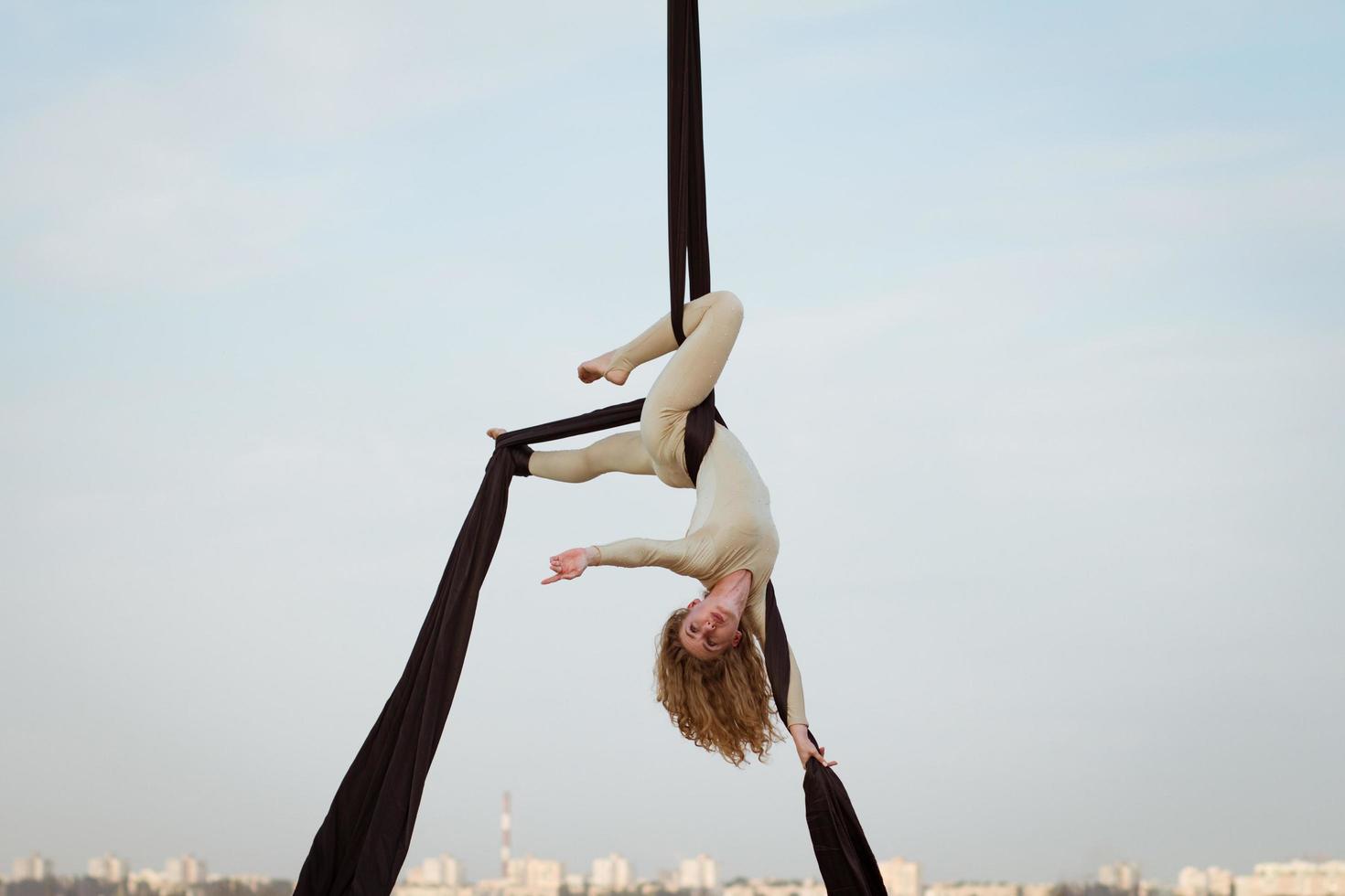 exercises with aerial silk outdoor, sky background. beautiful fit woman training acrobatic in airt. photo