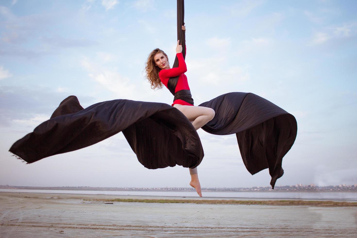 exercises with aerial silk outdoor, sky background. beautiful fit woman training acrobatic in airt. photo